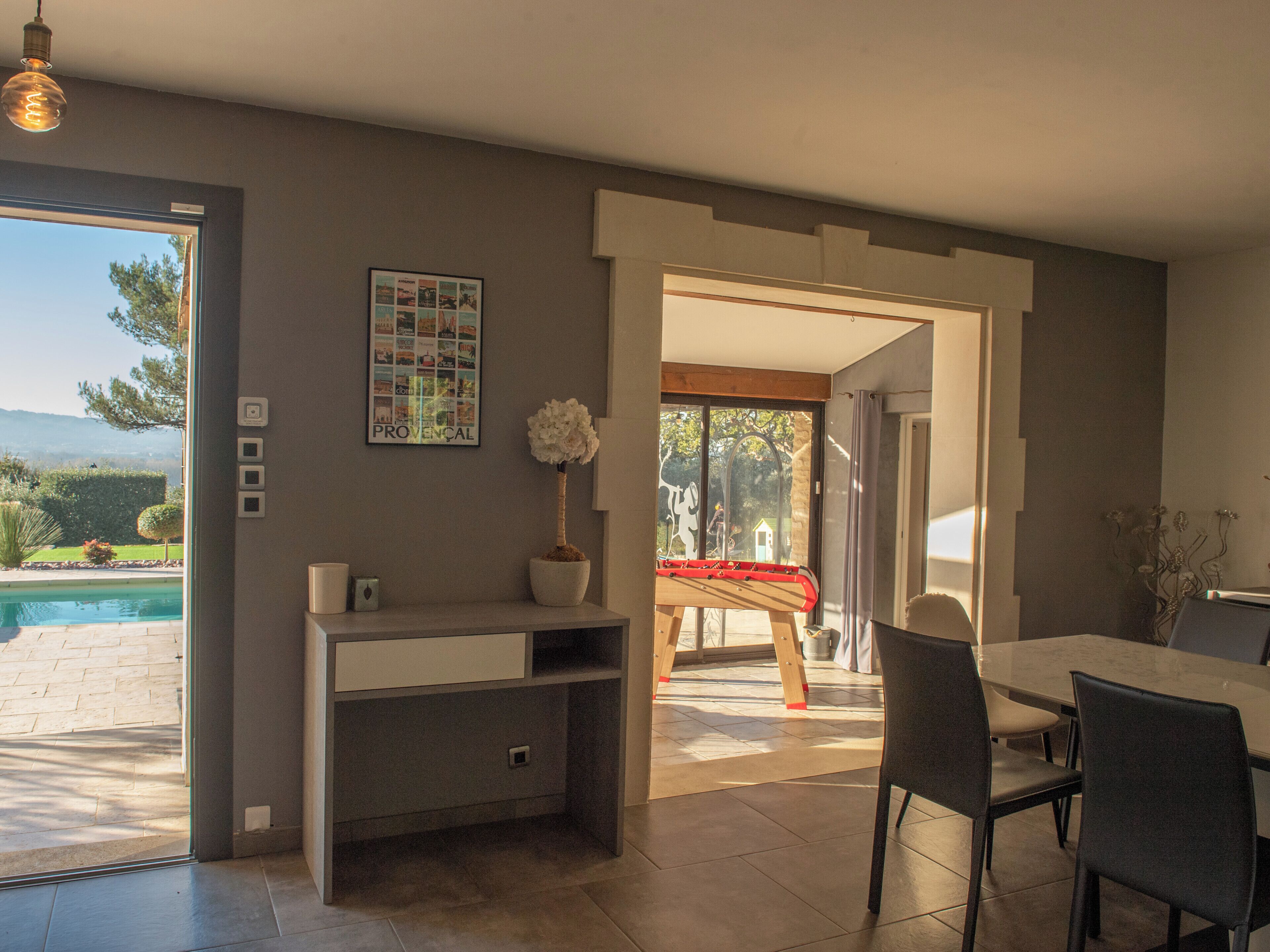 Une cuisine moderne avec un coin repas, une vue sur la piscine et un tableau encadré au mur.