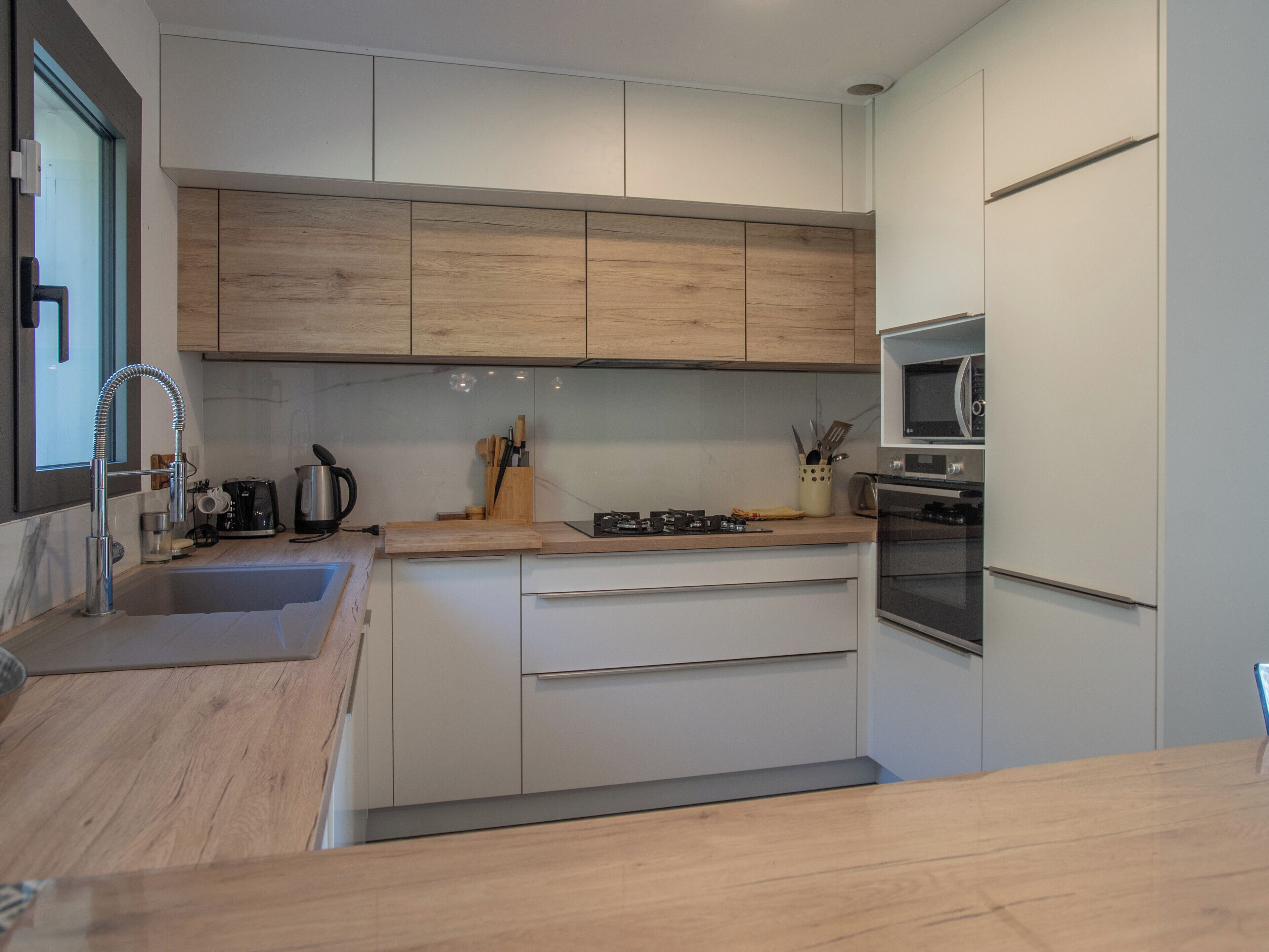Une cuisine moderne avec des meubles en bois, un évier en acier inoxydable, une cuisinière à gaz et un four encastré.