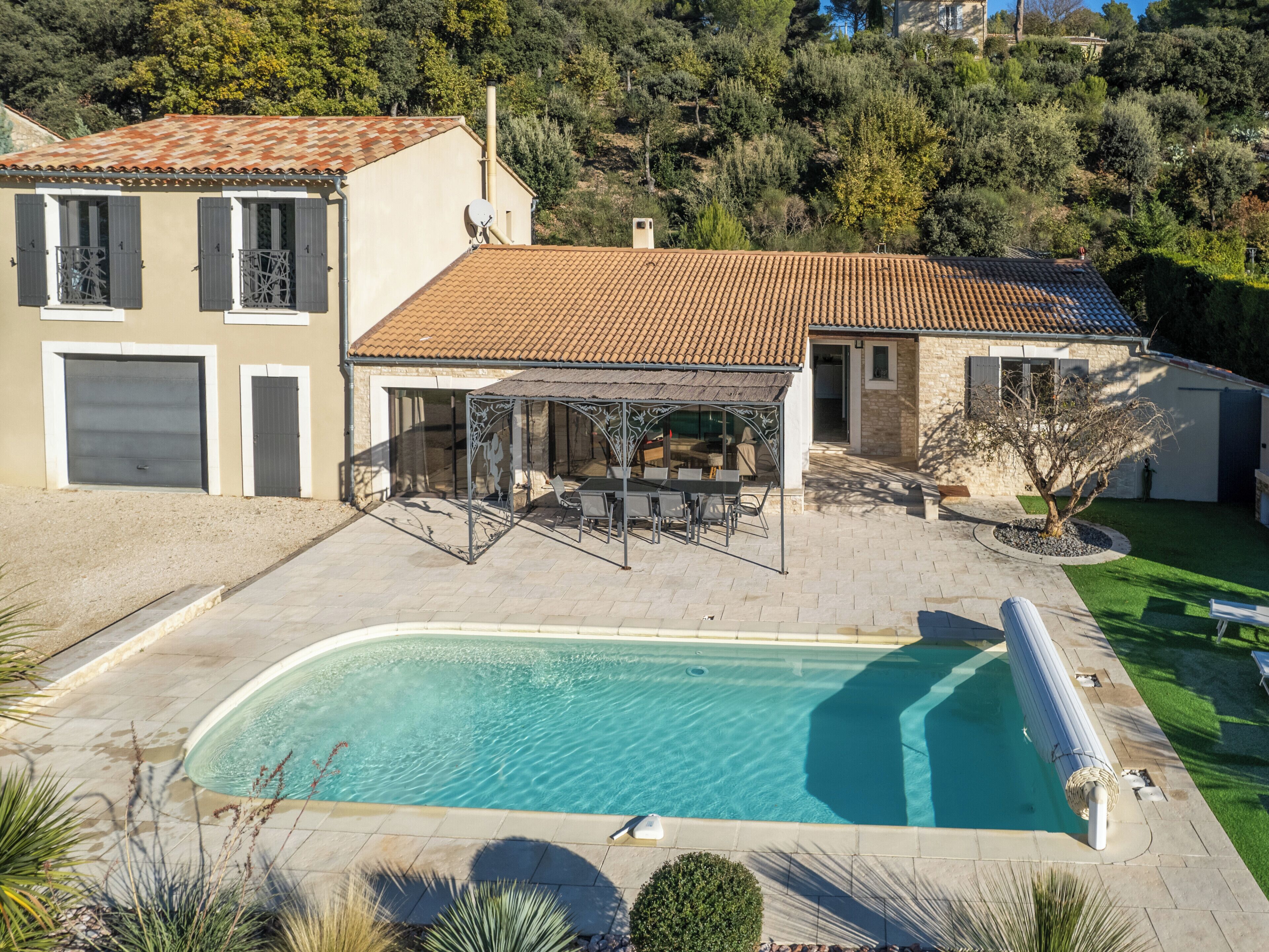 A residential property with a swimming pool, patio area, and a covered outdoor seating space.