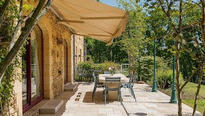 An outdoor patio with a stone wall, a table with chairs, and a canopy.