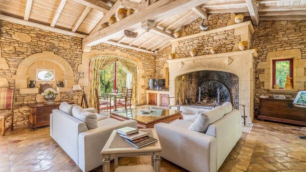 A rustic interior with stone walls, a fireplace, and a cozy seating area.