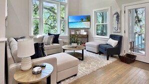 Amplia sala de estar con televisor grande, asientos cómodos y ventanas grandes que ofrecen vistas al exterior.