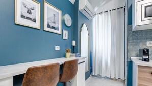 Een moderne keuken met een wit aanrecht, een koffieapparaat en een klok aan de muur.