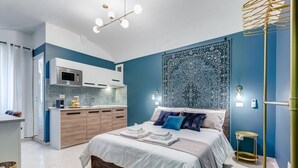 Een moderne slaapkamer met een bed, nachtkastjes en uitzicht op de keuken.