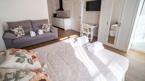 Et soveværelse med seng, sofa, skrivebord og garderobeskab.