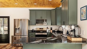 A modern kitchen with green cabinets, stainless steel appliances, and a wooden ceiling. - Family Friendly Modern Cabin w/ Hot Tub, Fire Pit & EV Charger - Lost River WV (Lost City)