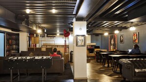 Un espacio interior acogedor con mesa de futbolín, zonas de estar y obras de arte en las paredes.