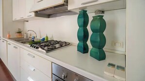 Una cocina con armarios blancos, una estufa a gas y jarrones decorativos color turquesa.