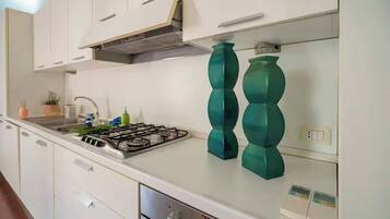 A kitchen with white cabinets, a gas stove, and teal decorative vases.