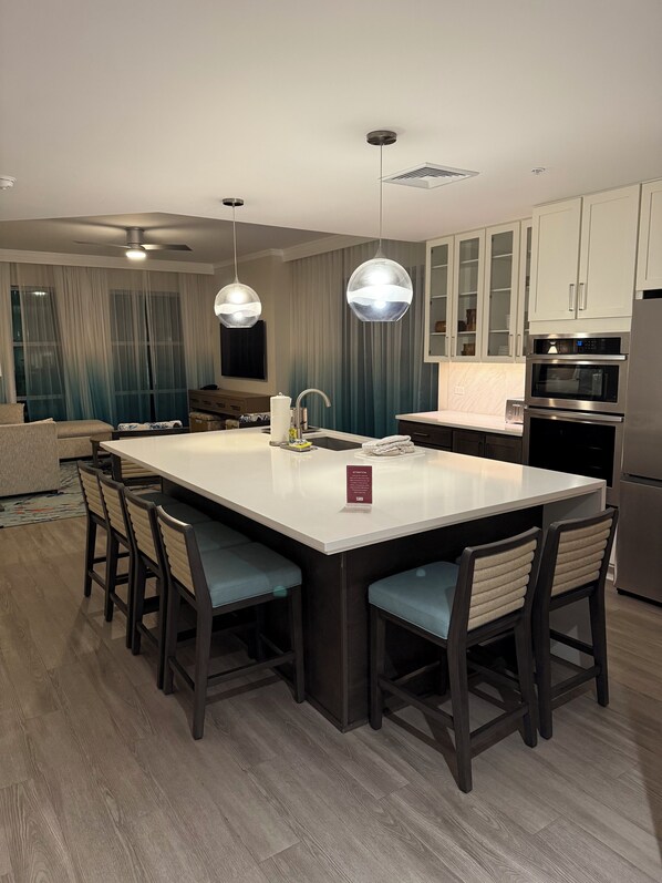 A modern kitchen with a central island, bar stools, stainless steel appliances, and pendant lighting. - Rare, Luxury, 3 Bedroom/2 Bathroom Oceanfront Condo in Myrtle Beach, SC (Myrtle Beach)