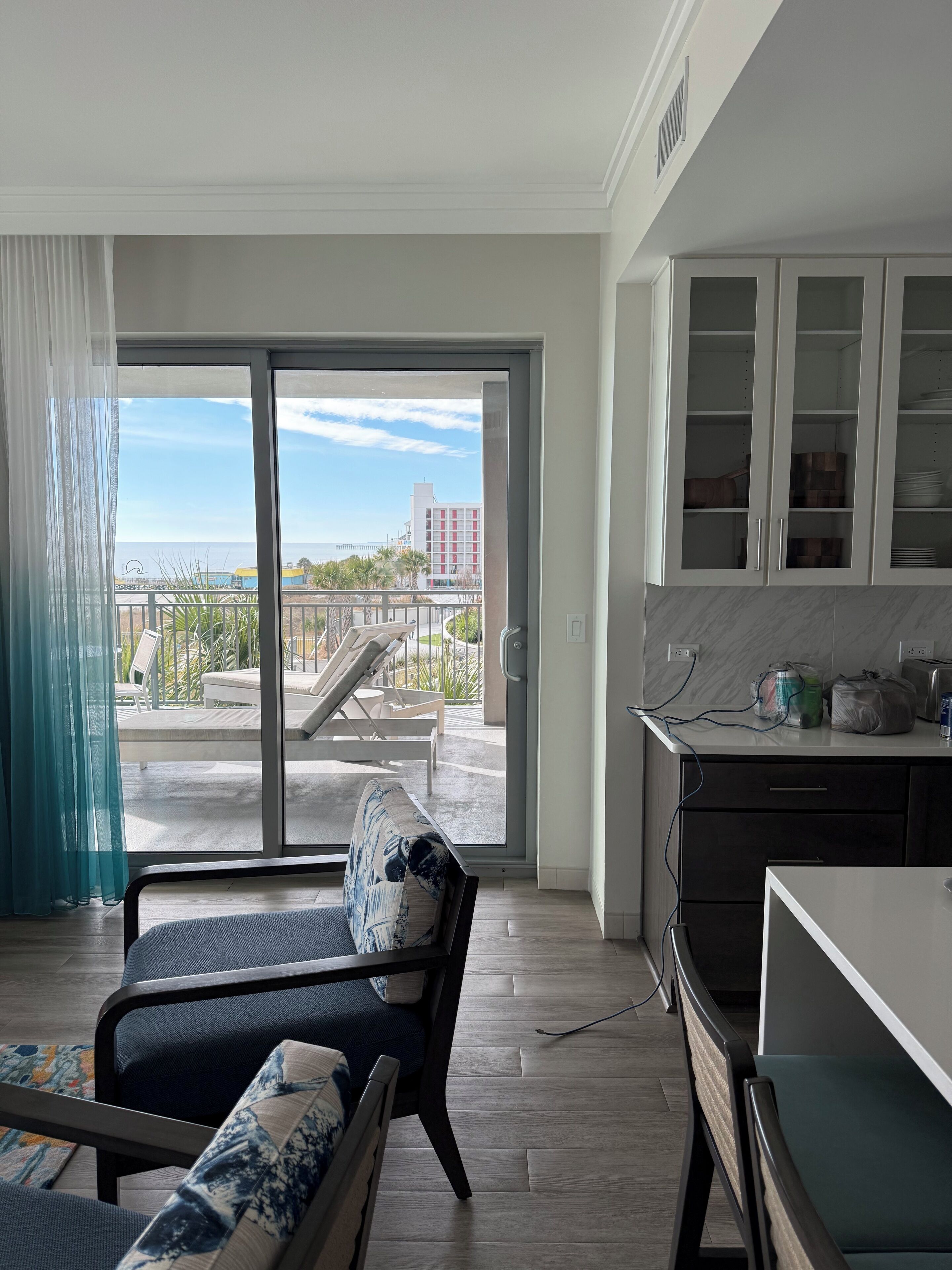 Um apartamento moderno com varanda, sofá, mesa de jantar e cozinha.