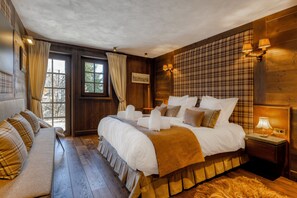 A spacious bedroom with a large bed, a sofa, and a wooden floor. - MAISON DOMINOS Chalet de Luxe, 5 chambres, Vue Mont Blanc, Spa, Jacuzzi, Salle de sport (Saint-Gervais-les-Bains)