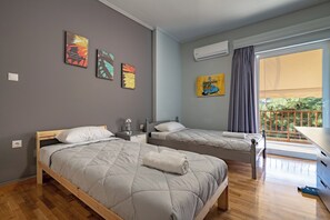 Ein modernes Schlafzimmer mit zwei Betten, einem kleinen Schreibtisch und Kunstwerken an den Wänden.