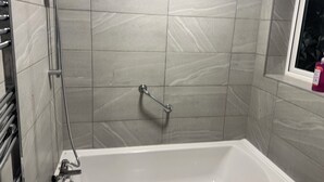 A bathroom with a bathtub, a shower, and a window. - Corporate 3bedroom home with parking (Erith)