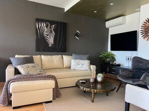 Ein modernes Wohnzimmer mit einer Couch, einem Couchtisch und einem an der Wand befestigten Flachbildfernseher.