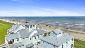 Una propiedad frente a la playa con varias casas, una playa de arena y el océano al fondo.
