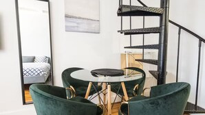 A modern room with a spiral staircase, a round dining table with chairs, and a large mirror on the wall. - Chic Urban Retreat: Duplex with Private Roof Deck (New York)