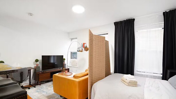 A modern hotel room with a bed, a desk with a computer, a TV, and a window with curtains. - ★ NEWLY RENOVATED STUDIO IN PRIME LOCATION - UES ★ (New York)