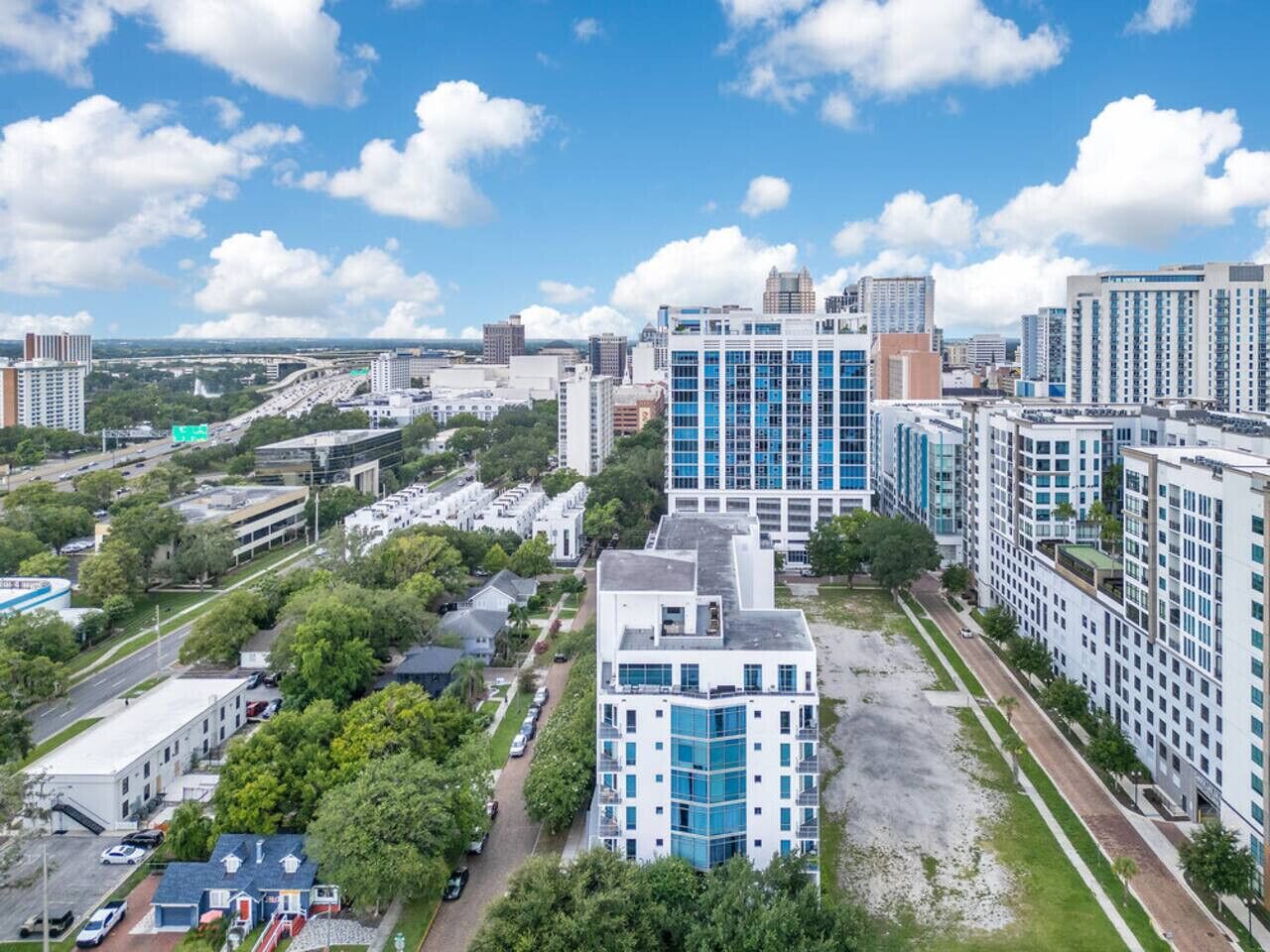 A modern urban area with high-rise buildings, a parking lot, and green spaces.