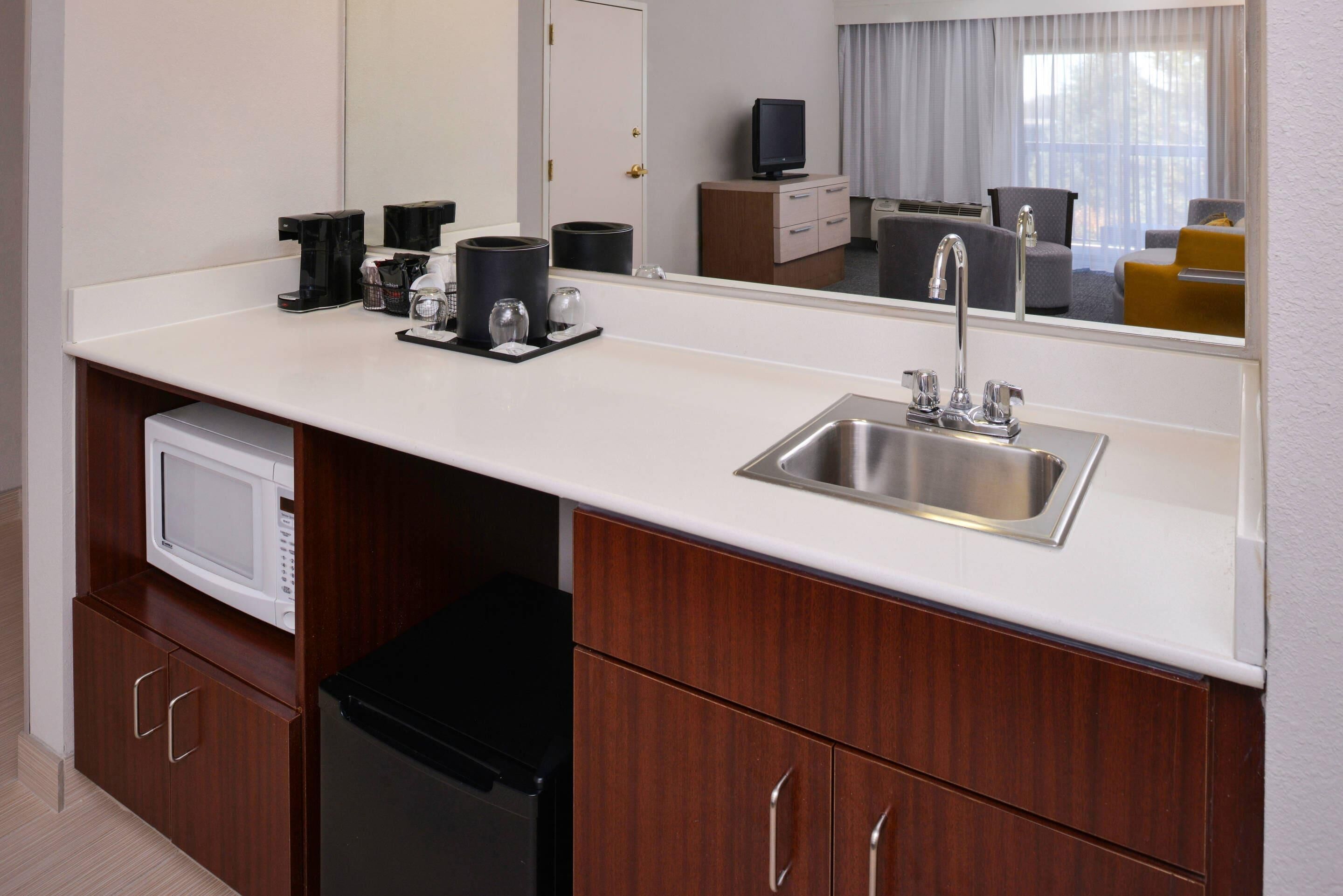A compact kitchenette with a microwave, coffee maker, and sink.