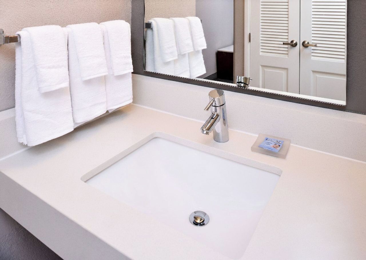 A modern bathroom with a white sink, a mirror, and a towel rack.