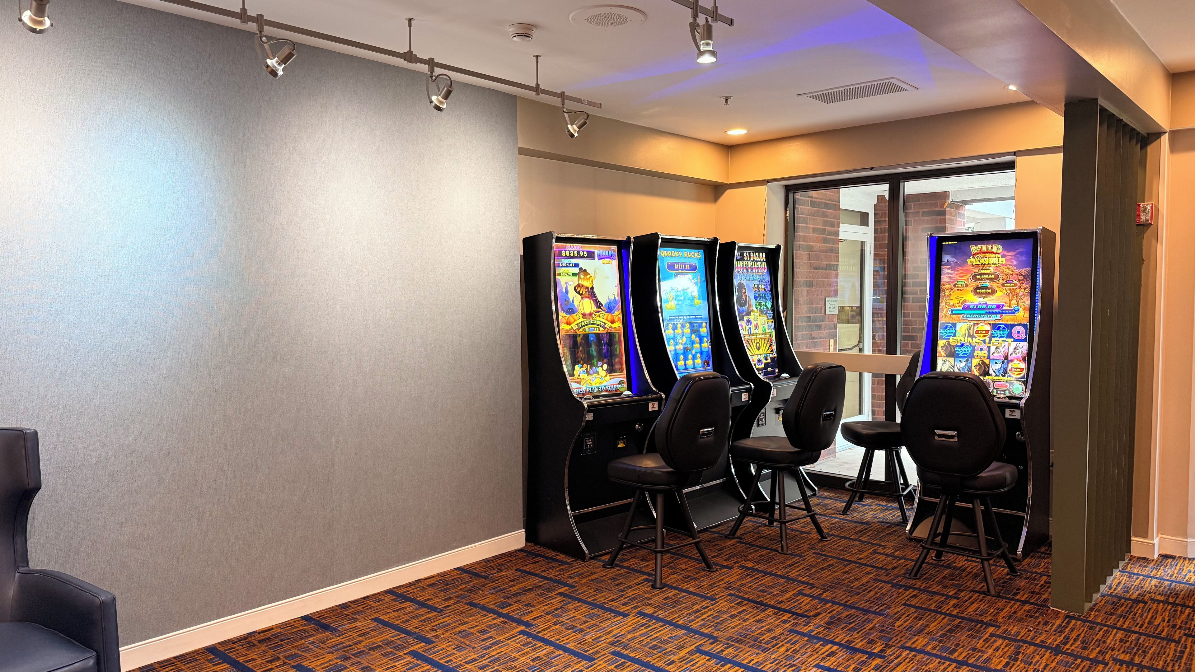 A room with four gaming machines, a carpeted floor, and a door leading outside.