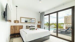 A modern bedroom with a large bed, a wooden headboard, a large window with a view of the outdoors, and a TV mounted on the wall. - Villa Seabreeze & Mistico Beach Club + Boat Shuttle (San Pedro)