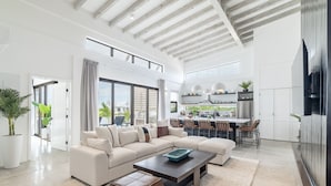 A spacious living room with a large sofa, a coffee table, and a dining area with chairs. - Villa Seabreeze & Mistico Beach Club + Boat Shuttle (San Pedro)