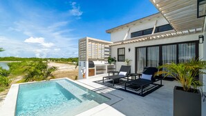 A modern outdoor pool area with lounge chairs and a view of the ocean. - Villa Seabreeze & Mistico Beach Club + Boat Shuttle (San Pedro)
