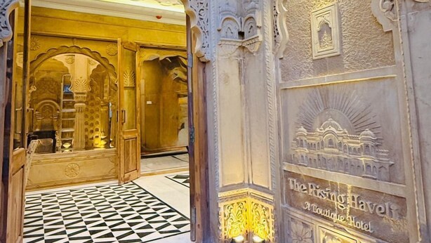 An ornate entrance with intricate carvings and a sign for The Rising Havell Boutique Hotel. - The Rising Haveli (Jaisalmer)