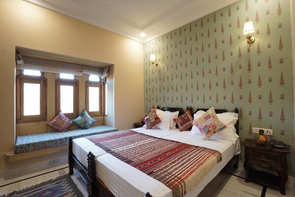 Una camera da letto con un letto grande, una panca vicino alla finestra e carta da parati decorata.