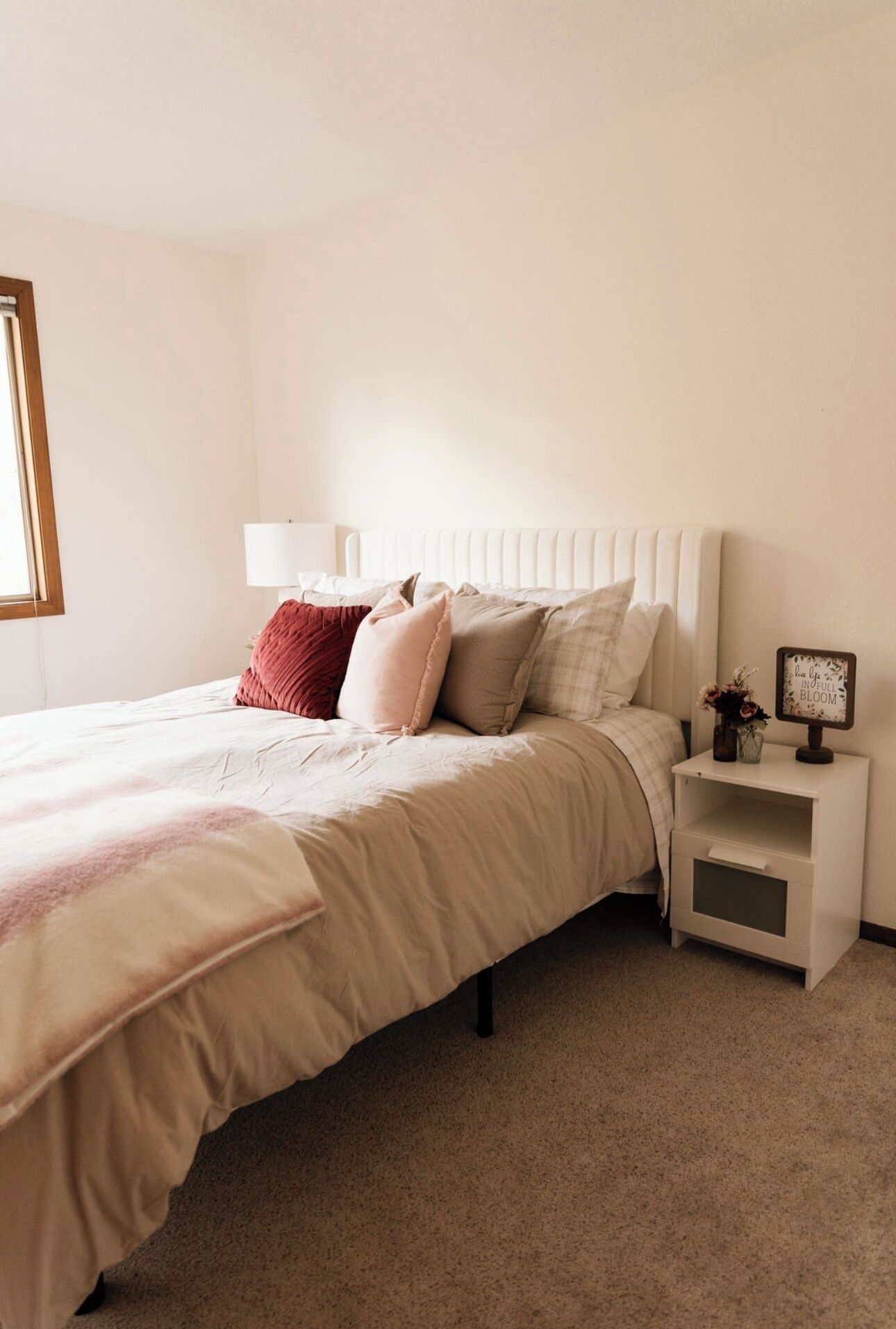 A neatly arranged bedroom with a bed, bedside table, and a nightstand.