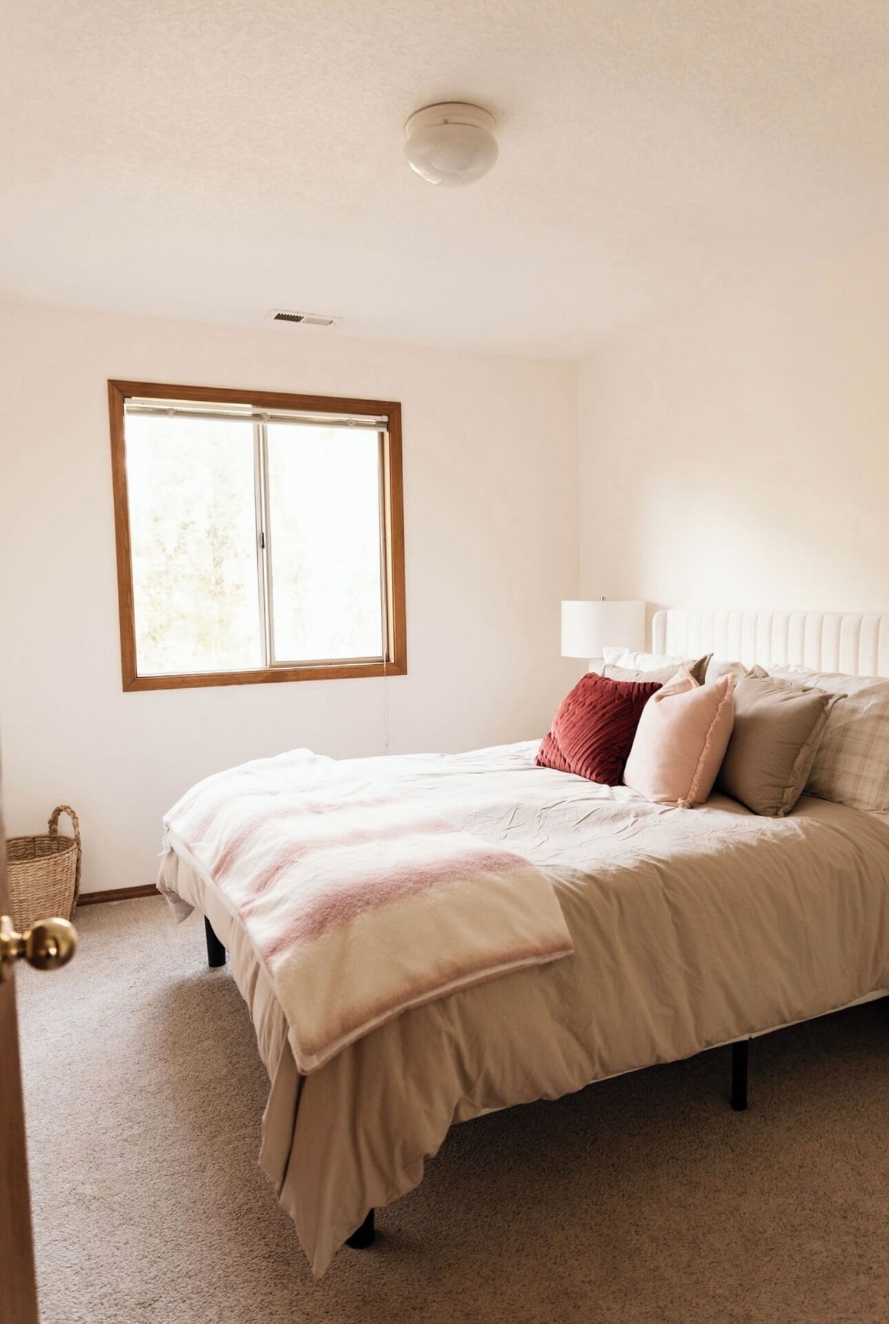 A bedroom with a bed, a window, a bedside lamp, and a ceiling light.