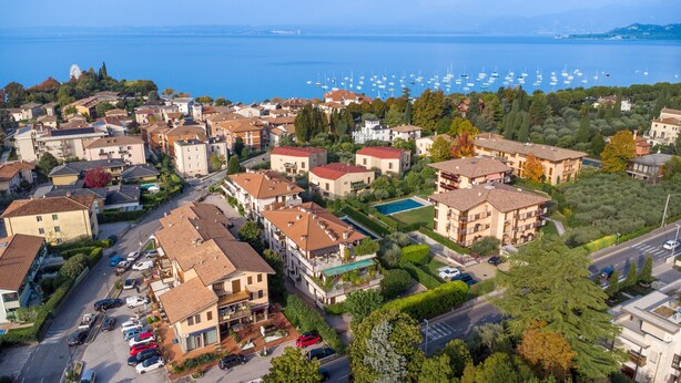 Une vue aérienne d’un quartier résidentiel situé sur la côte, avec de nombreux immeubles, une marina remplie de bateaux et une vue dégagée sur la mer.