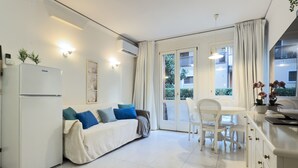 Une cuisine moderne avec des meubles blancs, un four encastré et un coin repas comprenant une table et des chaises blanches.