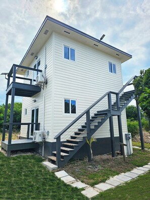 Ein zweistöckiges Gebäude mit Balkon, Treppe und Klimaanlage.