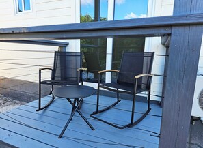 Eine Terrasse mit zwei schwarzen Stühlen und einem kleinen Tisch.