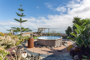 Un jardin avec un jacuzzi, une pergola et diverses plantes.