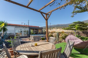 A wooden pergola with a pool table, chairs, and a cushioned chair under a clear sky. - Apartment with Sea View and Pool, Wi-Fi Included (La Sabinita)