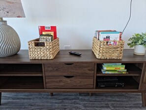 A wooden TV stand with two woven baskets containing books and DVDs.