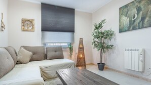 Una sala de estar moderna con un sofá, una mesa de centro, una planta en maceta y obras de arte en las paredes.