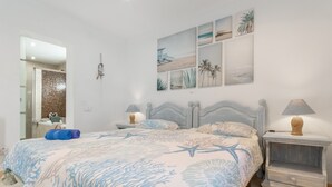 Un dormitorio con cama, mesitas de noche, un espejo y decoración en la pared.