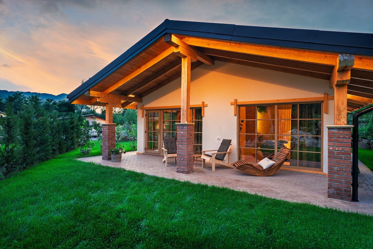 Une maison moderne dotée d’un patio couvert, de grandes fenêtres et d’une pelouse bien entretenue.