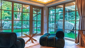 A room with large windows, a round ottoman, and a glass coffee table. - Thomhof Chalets (Bran)