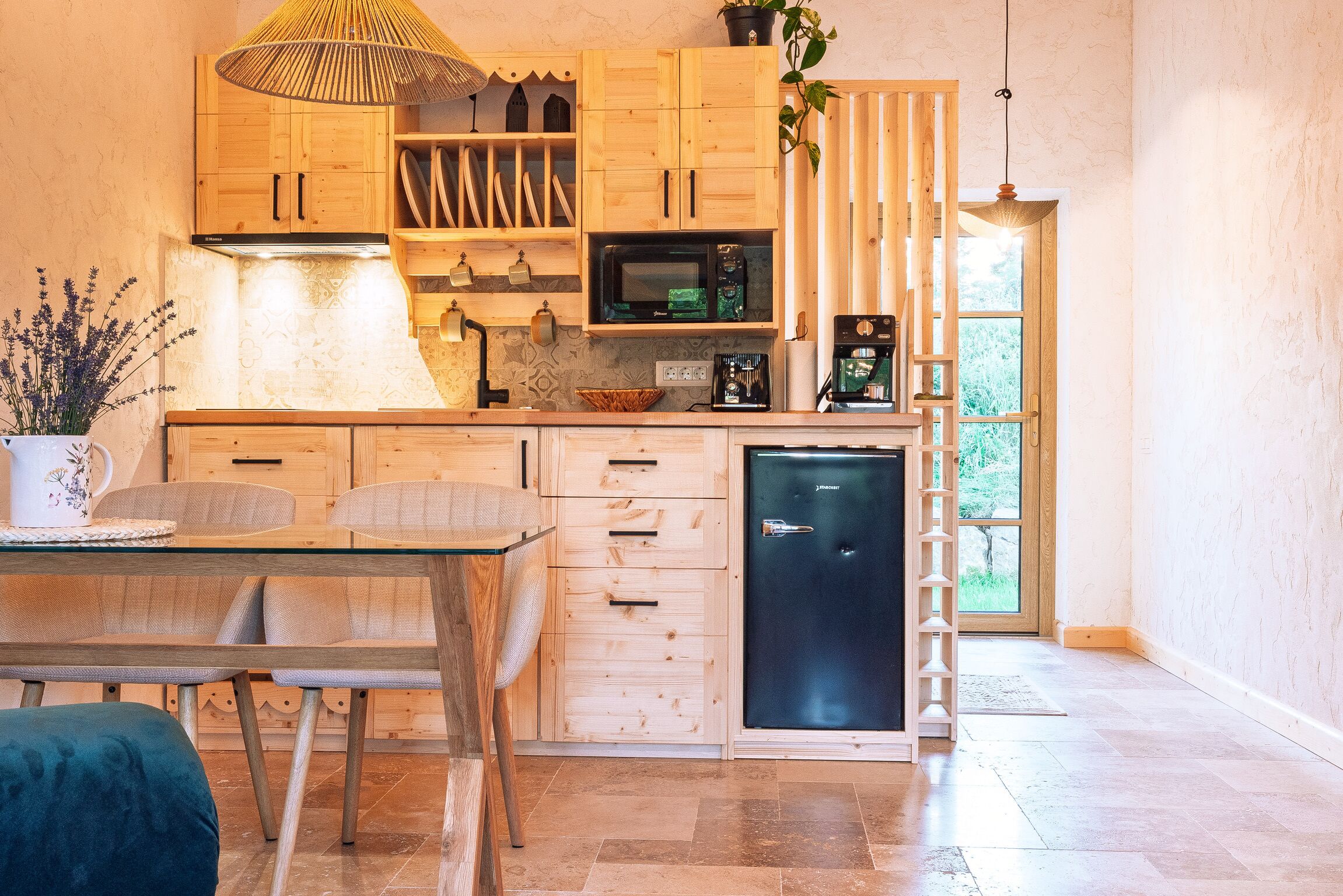 A modern kitchen with wooden cabinetry, a microwave, a coffee machine, and a refrigerator.