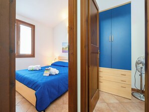 Une chambre à coucher avec un lit, une armoire, un ventilateur et une fenêtre.