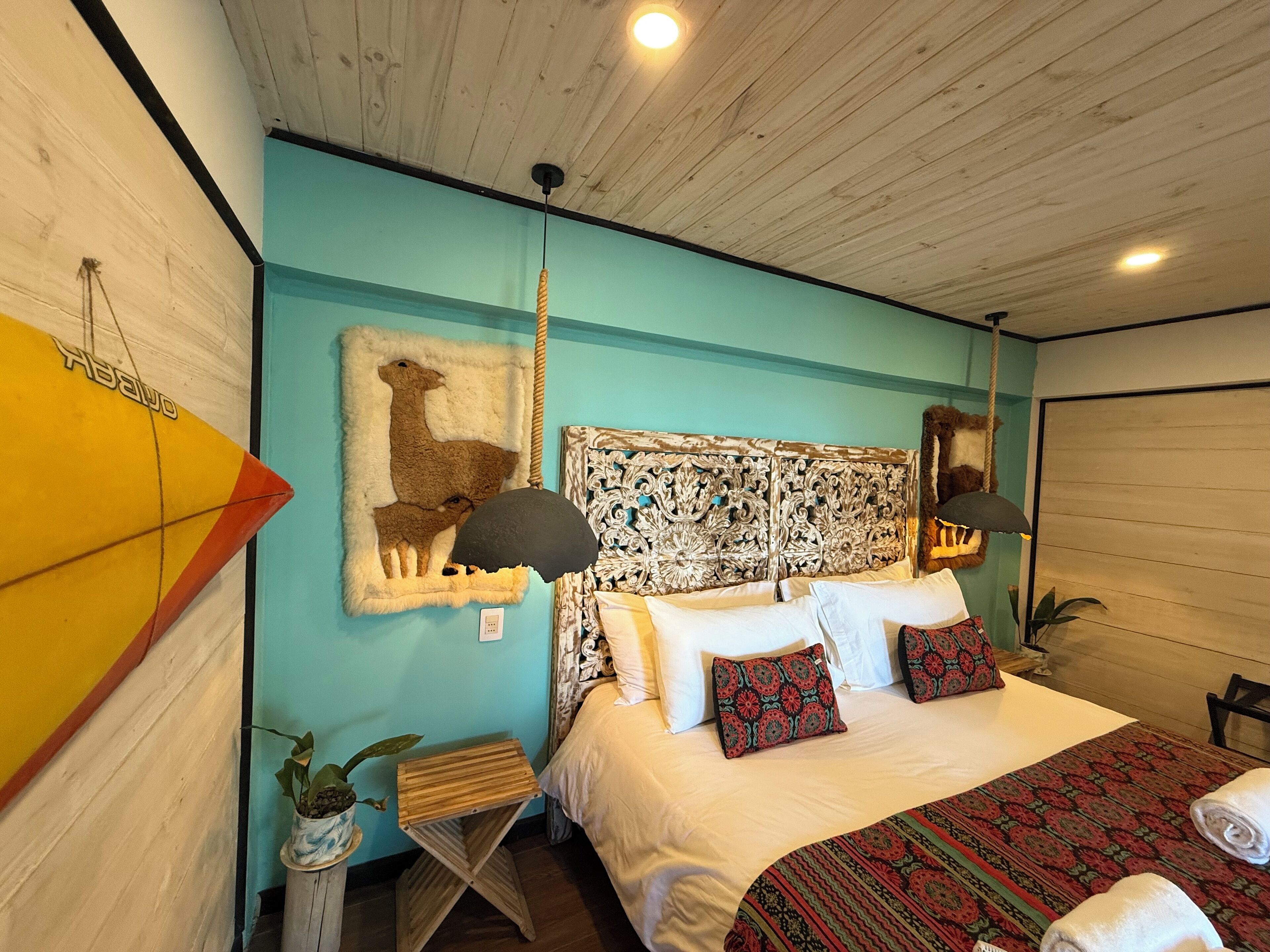 A bedroom with a bed, a wall-mounted mirror, a decorative headboard, and a wall art piece of a deer.