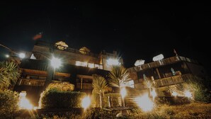 A multi-story hotel with illuminated balconies and outdoor lighting. - Ocean View Hot Tub Suites (Pichilemu)