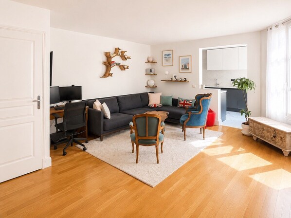 Uma sala de estar moderna com um sofá, cadeiras, uma escrivaninha e um computador.