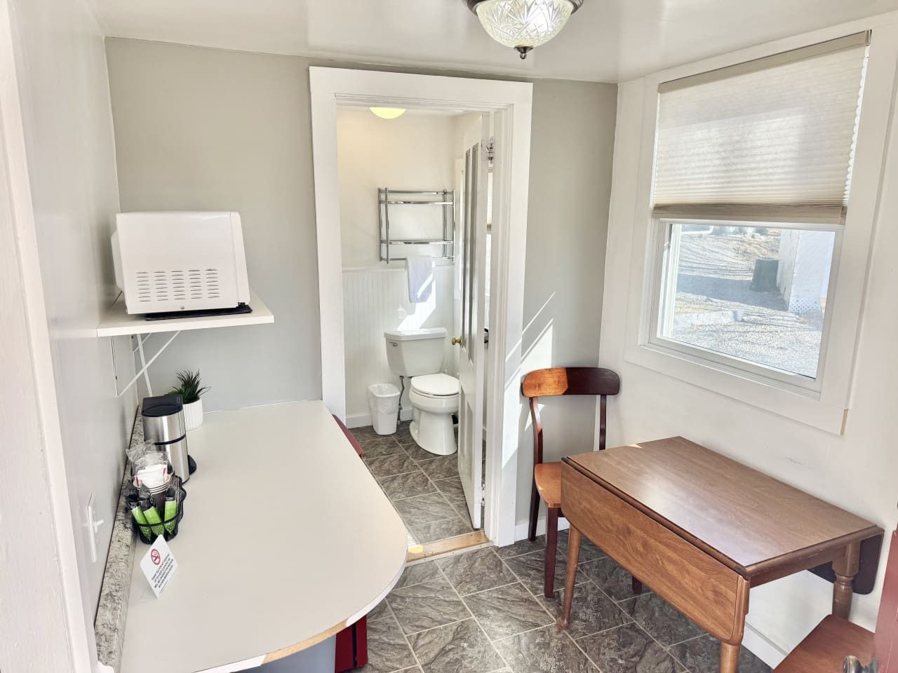 Een kleine badkamer met toilet, wastafel en een klein tafeltje.